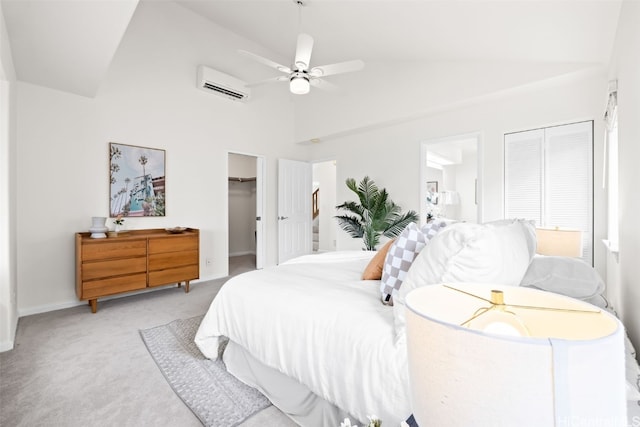 bedroom featuring a ceiling fan, ensuite bath, an AC wall unit, a spacious closet, and light carpet