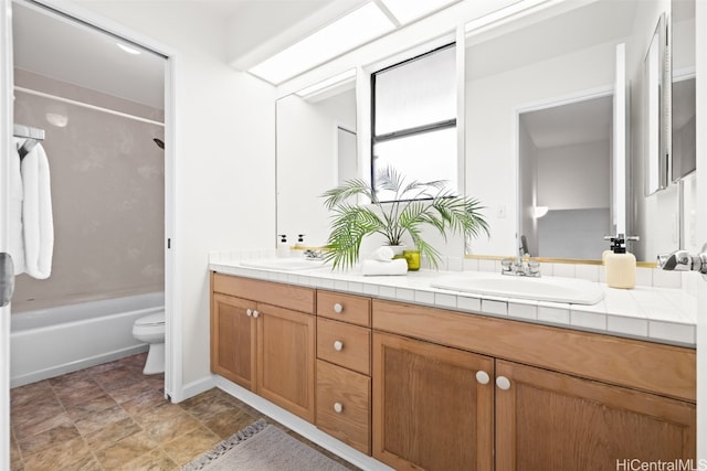 full bath featuring double vanity, shower / bath combination, toilet, and a sink