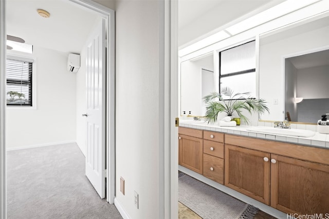 bathroom featuring a wall mounted AC, double vanity, baseboards, and a sink