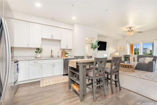 kitchen featuring a sink, light wood-type flooring, appliances with stainless steel finishes, and open floor plan