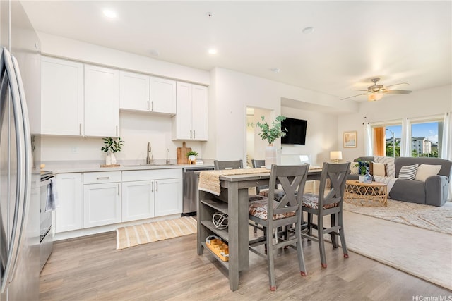 kitchen featuring white cabinets, open floor plan, stainless steel appliances, and a sink