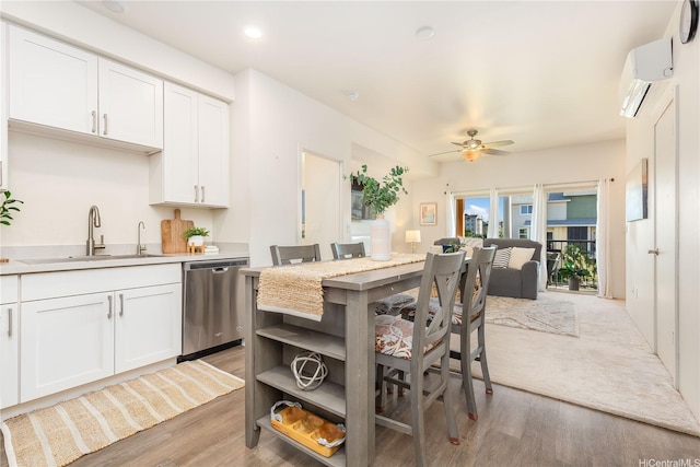 kitchen featuring light countertops, dishwasher, a sink, light wood-style floors, and white cabinetry