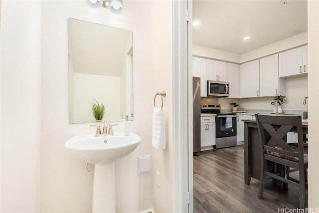 bathroom featuring recessed lighting, wood finished floors, and a sink