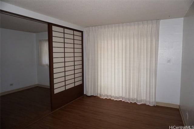 empty room featuring wood finished floors, baseboards, and a textured ceiling