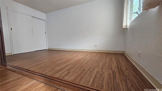 interior space featuring a closet, a textured ceiling, and wood finished floors