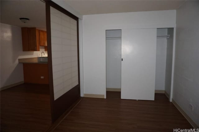 unfurnished bedroom featuring dark wood-style floors, a closet, and baseboards