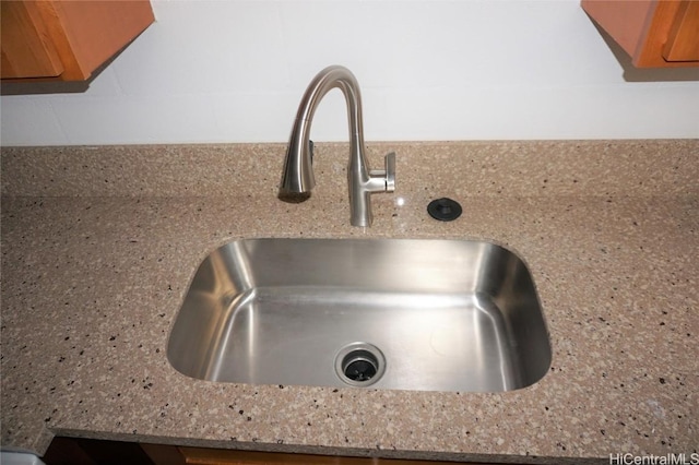 room details with light stone counters, brown cabinets, and a sink