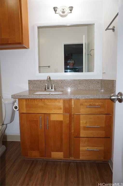 half bathroom with toilet, vanity, and wood finished floors