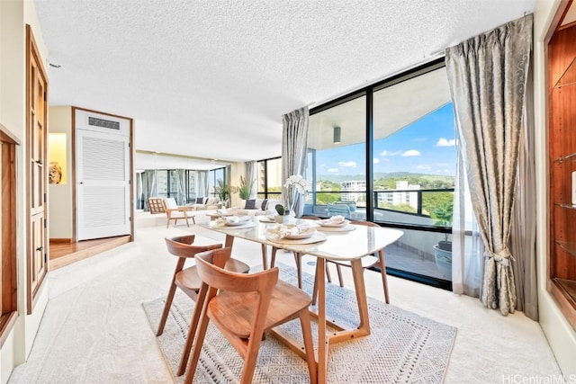 dining area featuring light colored carpet, a textured ceiling, and expansive windows