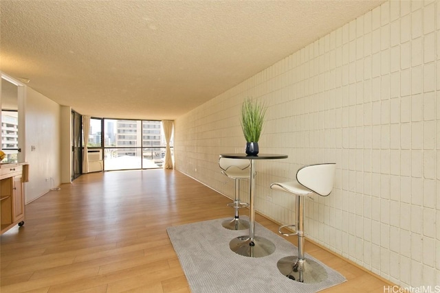 sitting room with floor to ceiling windows, light wood-style flooring, and a textured ceiling