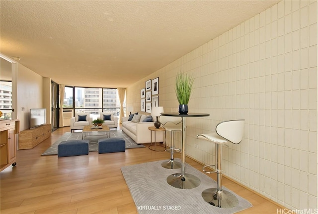 living area with tile walls, light wood-style floors, and a textured ceiling