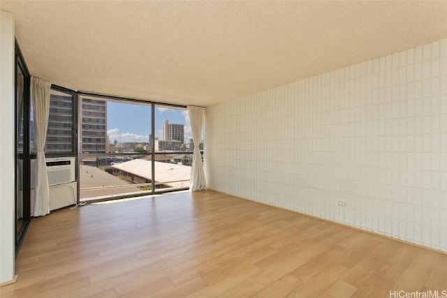 spare room with a textured ceiling, a city view, wood finished floors, and floor to ceiling windows