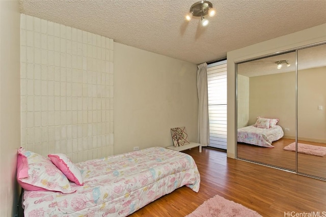 bedroom with a closet, a textured ceiling, and wood finished floors