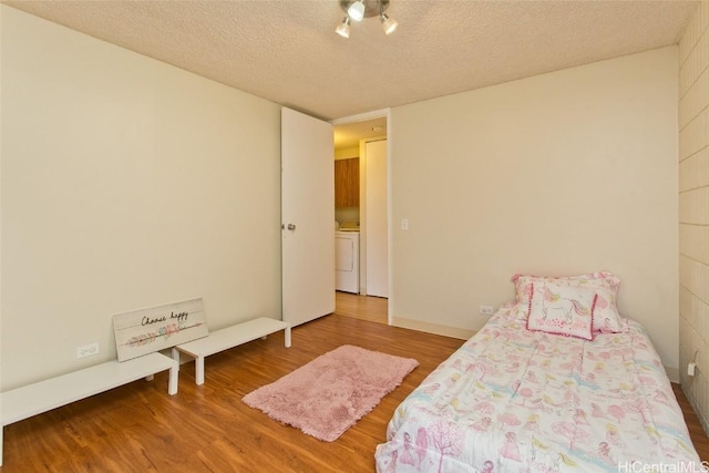 bedroom with washer / clothes dryer, a textured ceiling, and wood finished floors