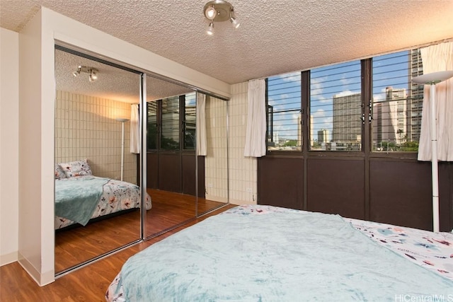 bedroom with a closet, a textured ceiling, and wood finished floors