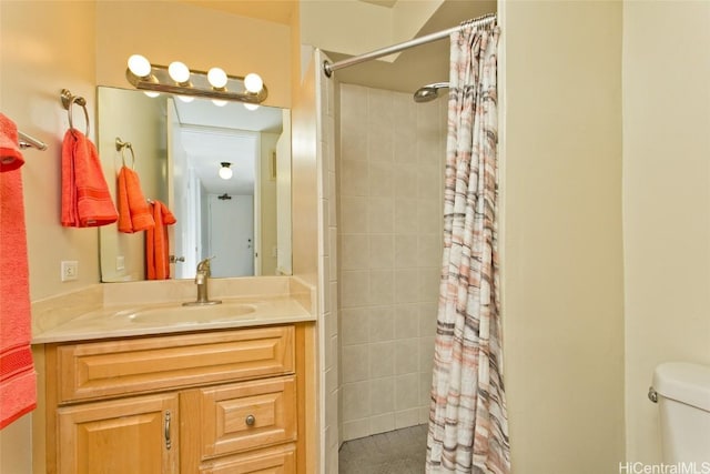 bathroom with toilet, tiled shower, and vanity