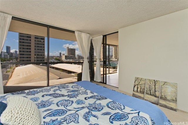 carpeted bedroom with access to outside, a city view, a textured ceiling, and expansive windows