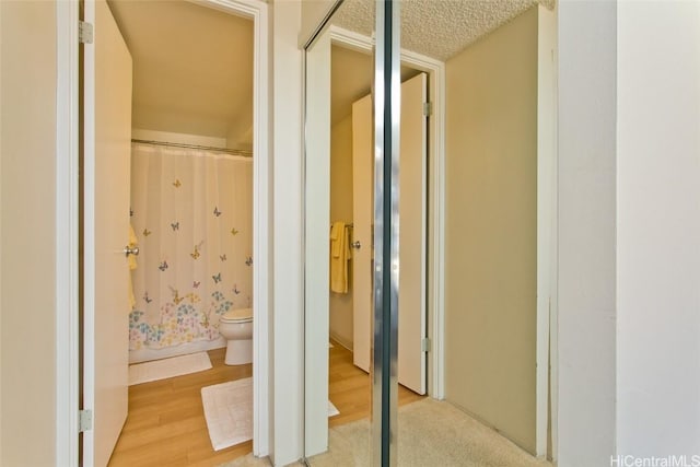 hall with wood finished floors and a textured ceiling