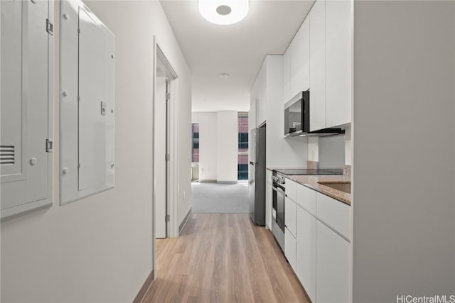 kitchen featuring light stone counters, light wood-style flooring, stainless steel appliances, white cabinetry, and modern cabinets