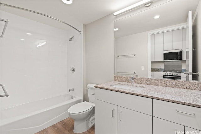 bathroom featuring washtub / shower combination, toilet, vanity, and wood finished floors