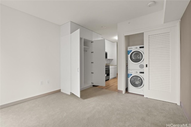 clothes washing area featuring a sink, laundry area, stacked washer and dryer, and light carpet