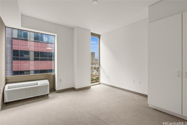 unfurnished room with baseboards, a city view, an AC wall unit, and carpet