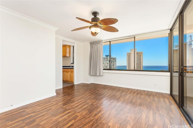 unfurnished room with crown molding, baseboards, dark wood-style flooring, and ceiling fan