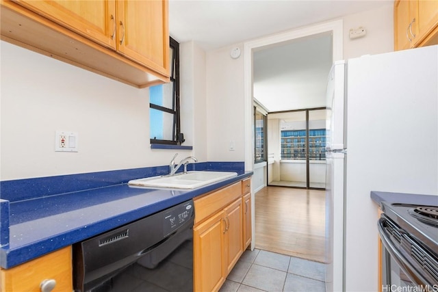 kitchen featuring light tile patterned floors, freestanding refrigerator, a sink, dishwasher, and dark countertops