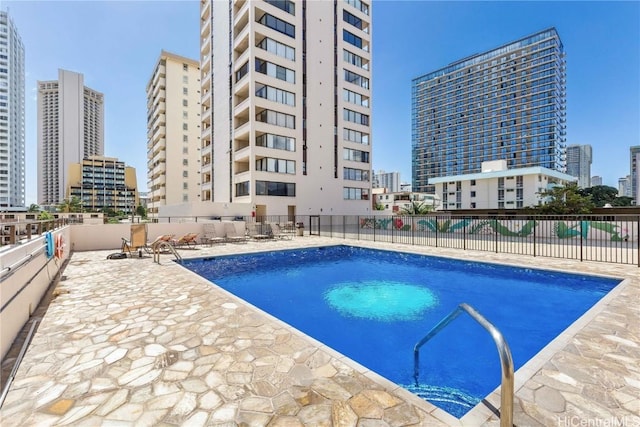 community pool with a patio, a city view, and fence