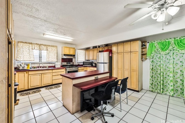 kitchen with light tile patterned flooring, a sink, stainless steel appliances, under cabinet range hood, and a textured ceiling