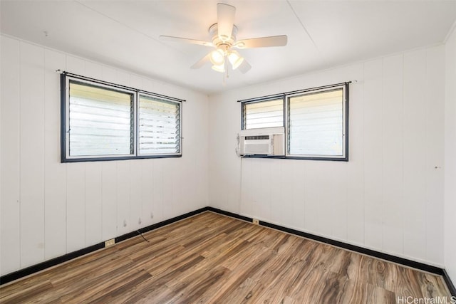 spare room featuring cooling unit, baseboards, wood finished floors, and a ceiling fan