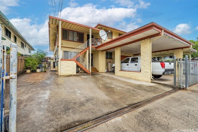 view of front of house with a carport, stairway, driveway, and fence