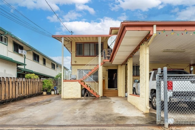 view of front facade with stairway, a carport, and fence