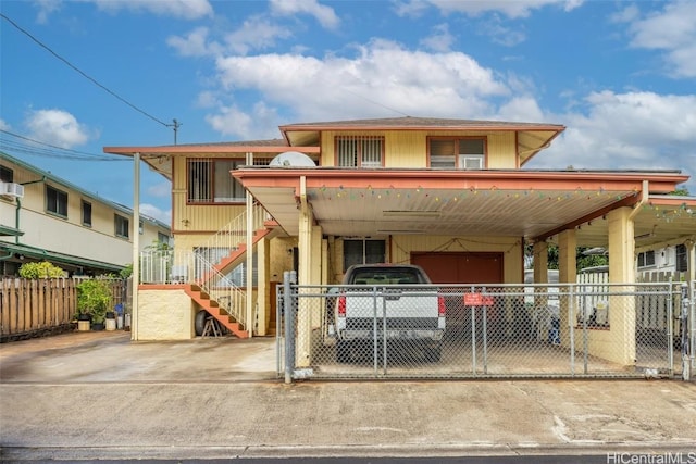 view of front of house with an attached carport, driveway, stairs, and fence