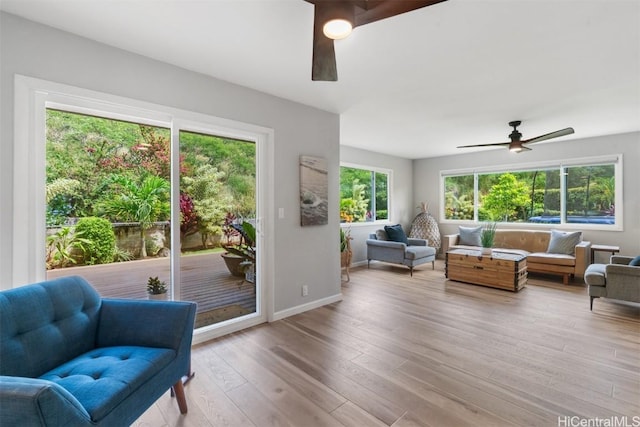 interior space featuring baseboards, a ceiling fan, and light wood finished floors