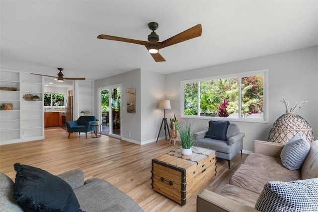 living area with a ceiling fan, baseboards, and light wood finished floors