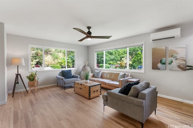 living room with a wall mounted air conditioner, baseboards, and light wood-style floors