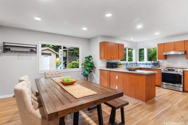 kitchen with under cabinet range hood, stainless steel range with electric stovetop, a peninsula, and light wood-style floors