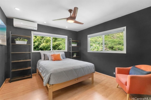 bedroom featuring baseboards, multiple windows, an AC wall unit, and wood finished floors