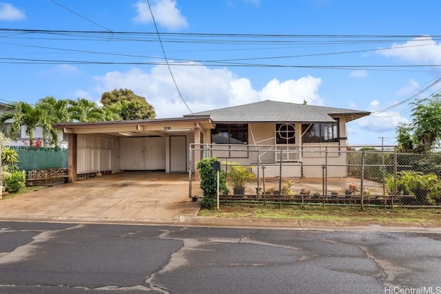 view of front facade with concrete driveway, fence, roof with shingles, and a carport