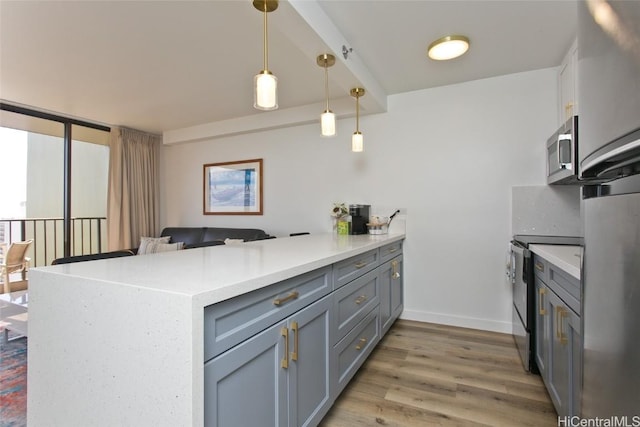 kitchen featuring stainless steel microwave, light countertops, electric range oven, a peninsula, and light wood-style floors