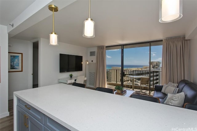 kitchen with visible vents, open floor plan, light countertops, a wall of windows, and hanging light fixtures