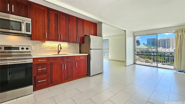 kitchen featuring a sink, light countertops, reddish brown cabinets, and stainless steel appliances