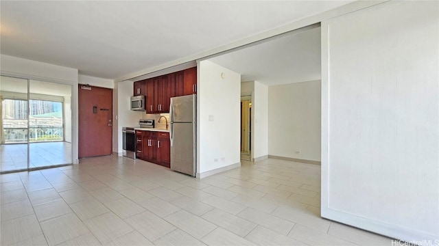 kitchen featuring baseboards, light countertops, appliances with stainless steel finishes, light tile patterned flooring, and reddish brown cabinets