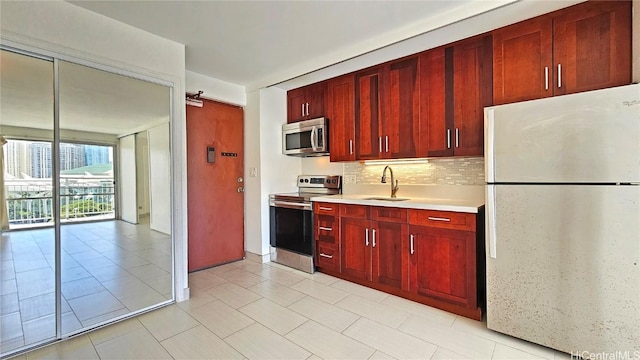 kitchen with a sink, stainless steel appliances, light countertops, decorative backsplash, and dark brown cabinets