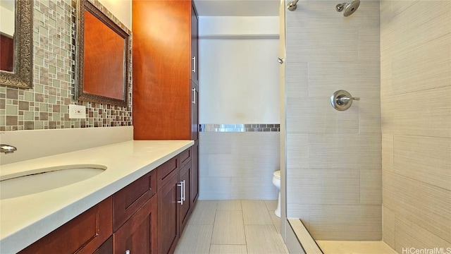 bathroom featuring toilet, vanity, tiled shower, tile patterned floors, and tile walls