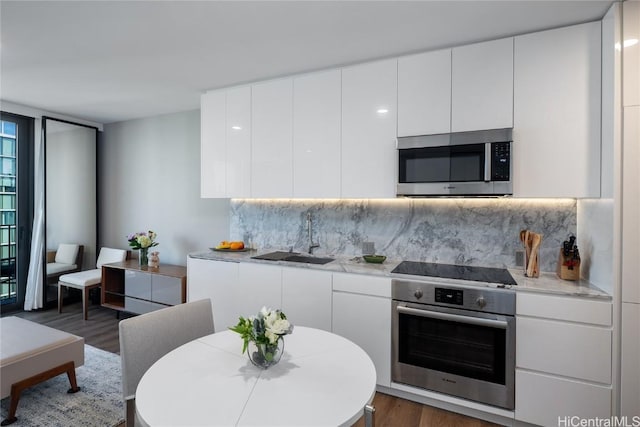 kitchen with backsplash, appliances with stainless steel finishes, light countertops, and a sink