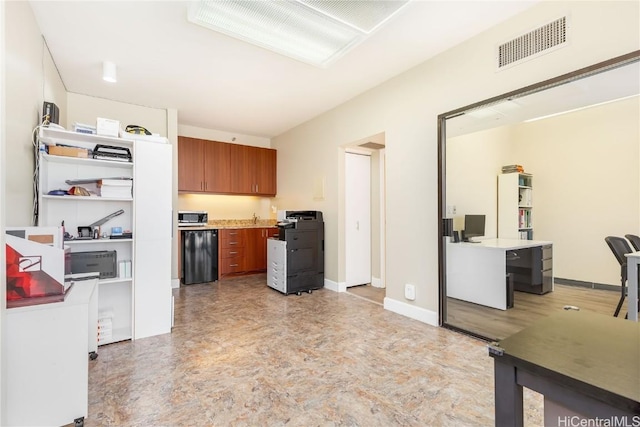 kitchen with brown cabinetry, visible vents, baseboards, light countertops, and stainless steel microwave