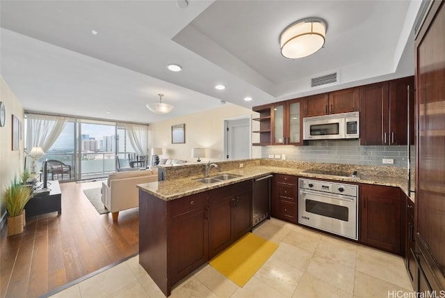 kitchen with visible vents, a tray ceiling, a peninsula, a sink, and stainless steel appliances