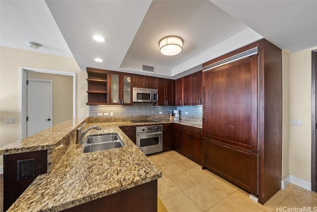 kitchen with light stone countertops, visible vents, a peninsula, a sink, and appliances with stainless steel finishes